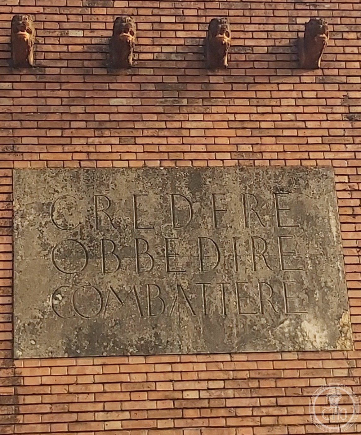 Ex Casa del Fascio — Rubano (Quirino De Giorgio, 1937–1939) — The stone slab in close-up: CREDERE OBBEDIRE COMBATTERE, incised in Roman capitals.