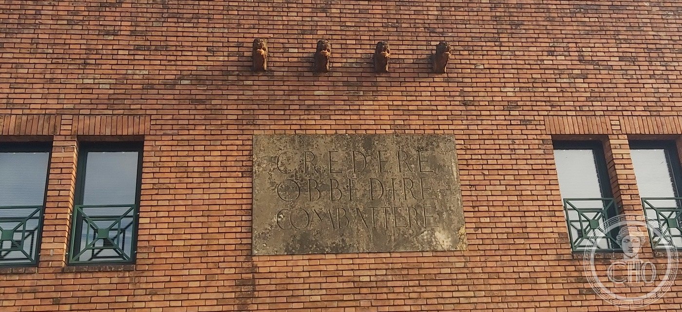 Ex Casa del Fascio — Rubano (Quirino De Giorgio, 1937–1939) — The four fasces consoles and the slogan slab, set between the upper windows.